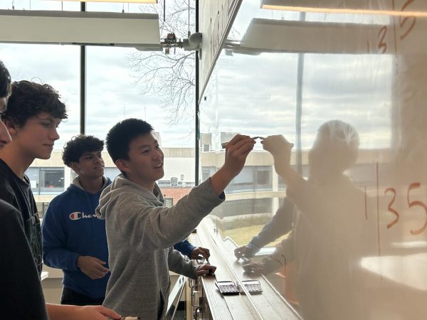 RISING STOCKS. Sophomore Trevor Hou draws out how the Stock Market Clubs stock simulator works on the white board. This club is a really immersive experience for you to truly understand the ins and outs of the stock market. It is a low-stakes kind of educational experience, Hou said. 