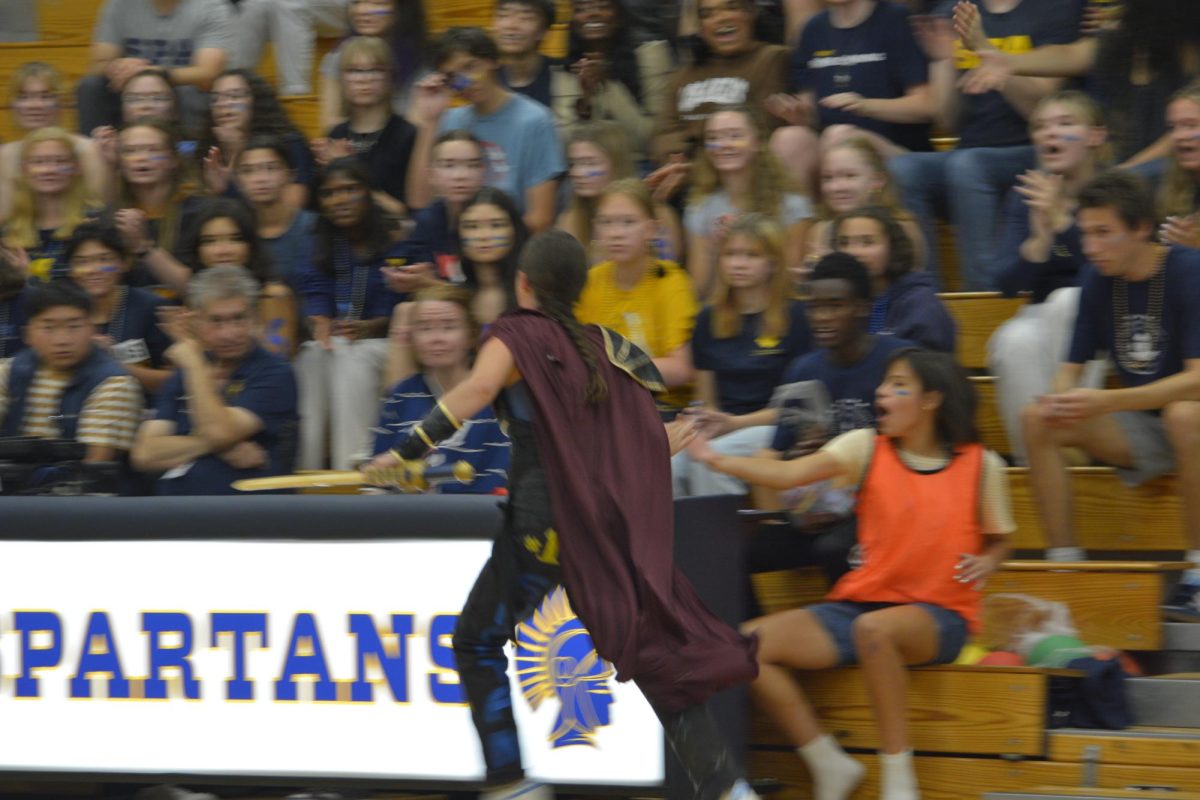 GET HYPE. The spartan runs by the packed bleachers, handing out high fives after defeating the crusader.