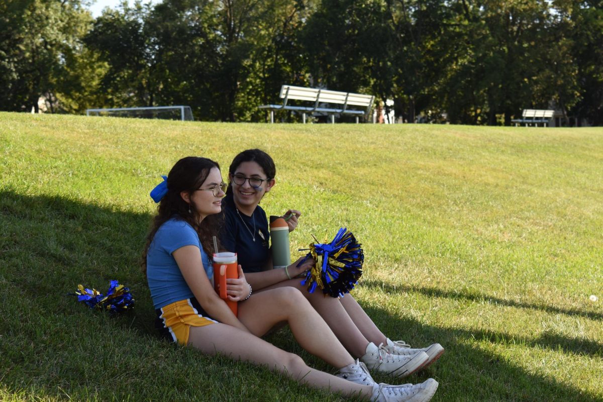 ANTICIPATION. Juniors Elzie Bieganek and Frances Matthews wait in the shade for the storming of the field to start.