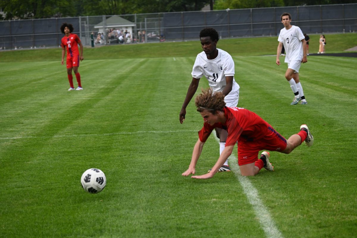 CONTROL. Senior Ezra Straub fights over possesion of the ball, causing a Scots player to trip and fall.