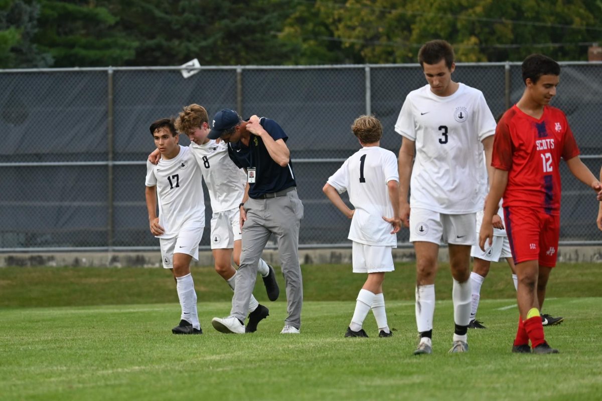 CAMARADERIE. Senior Arlo Zirps and Spartan coach helps an injured Rowan McLean off the field.