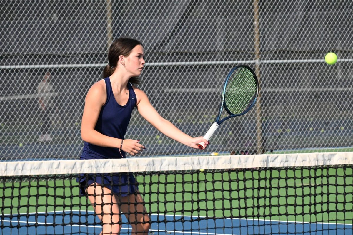 VOLLEY. Larson approaches the net to volley the ball after her opponent hits a short shot.