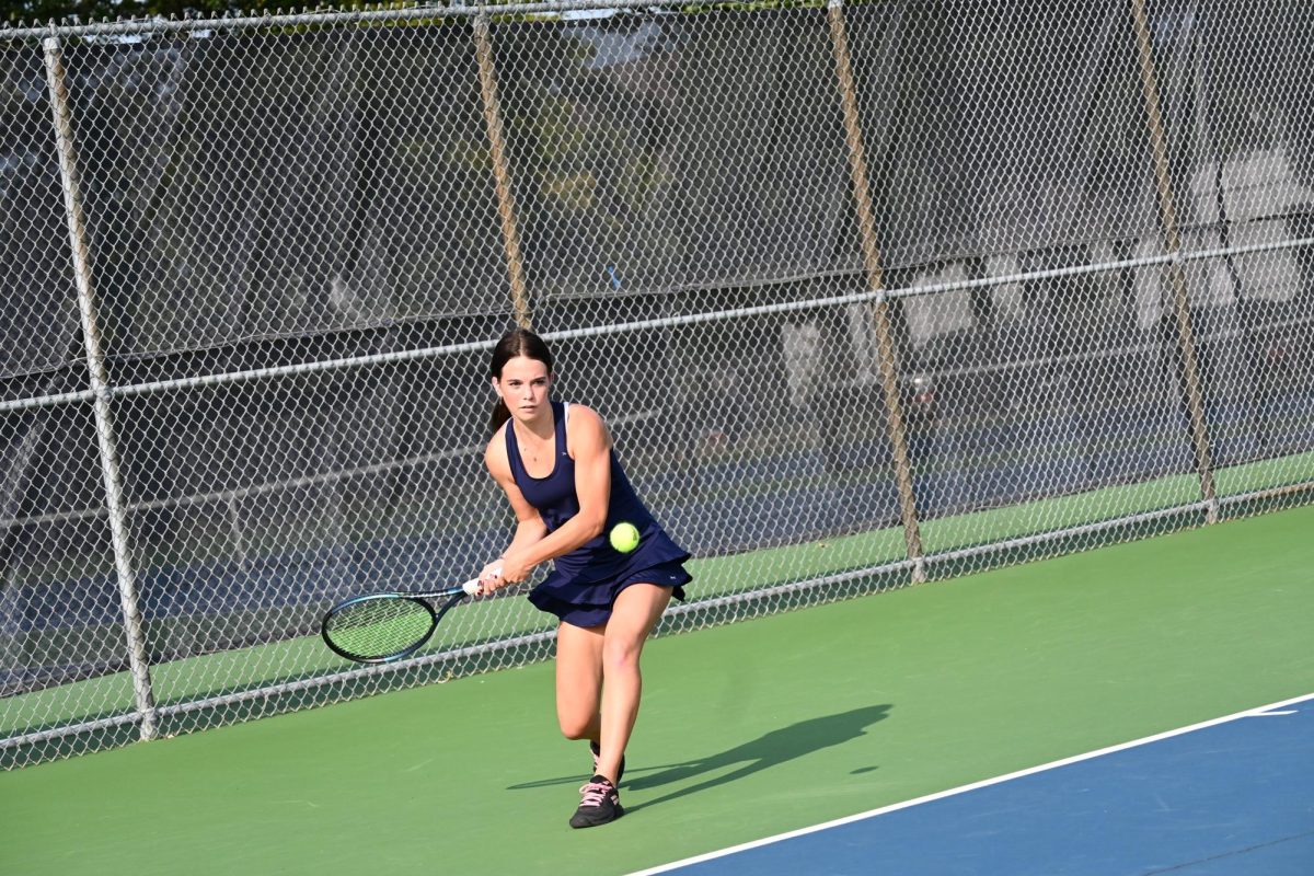 BACKHAND. Larson hits the ball using a backhand shot to return her opponent's serve and to win the point. 