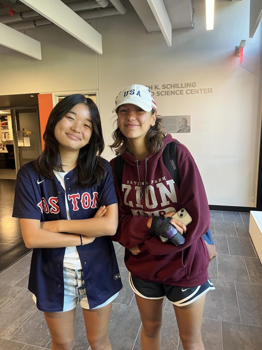 RED AND BLUE. Senior Scarlett Gibson (left) dons a blue and red baseball jersey. She paired the jersey with a white shirt underneath, and light blue jean shorts. Sophomore Naomi Glozman (right) sports a white hat embroidered with the letters "USA," and a red sweatshirt to match.