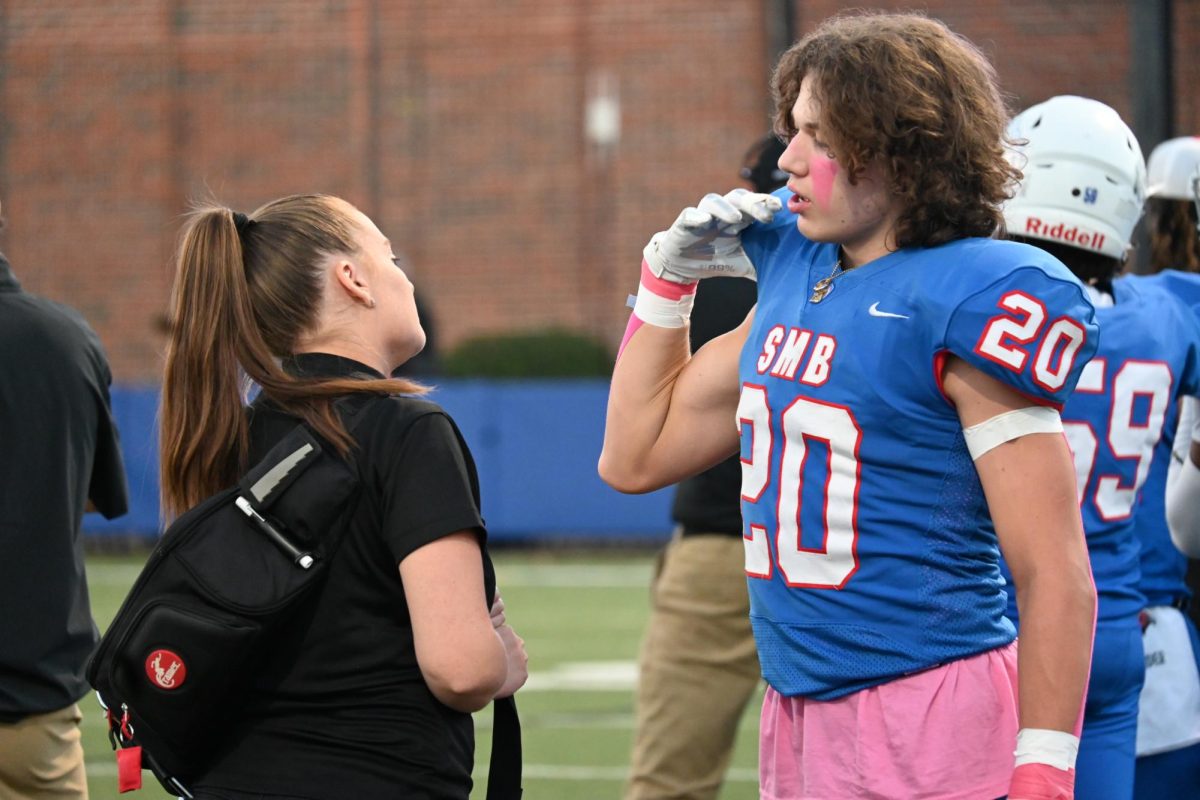 TALK TO A TRAINER. Junior Bennett Sauer shows the team trainer a sore spot on his shoulder. 