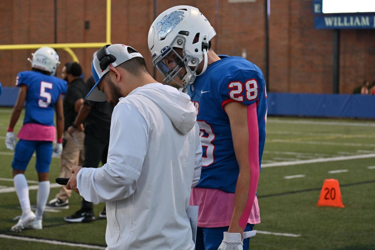 REWIND. Sophomore Adem Rivers watches a previous play with his coach. 