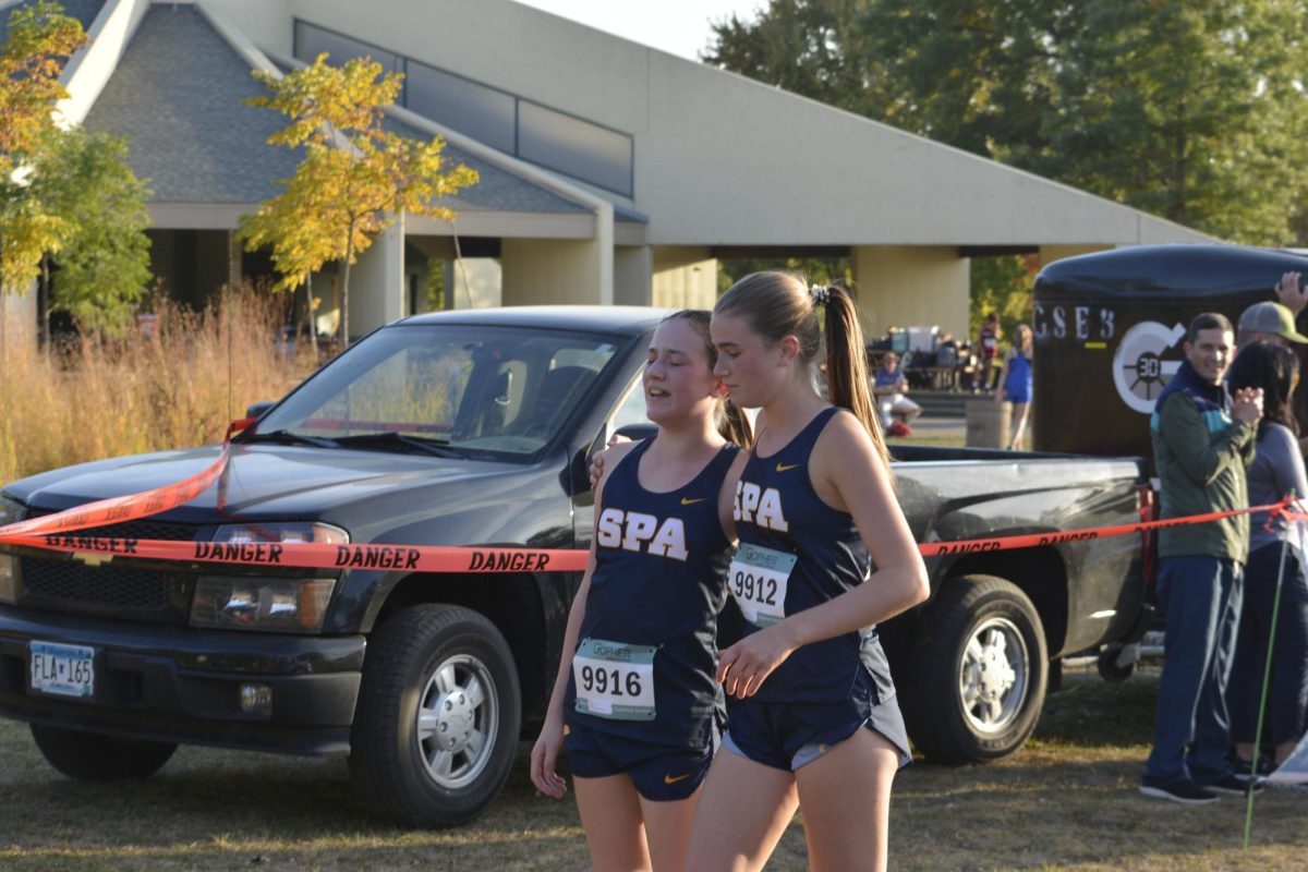 I GOT YOU. Senior Taylor Barkwell comforts 7th grader Isla Kim after she crosses the finish line. 