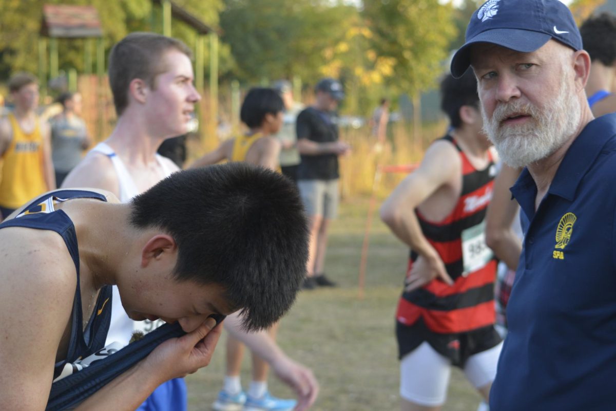 TAKING A BREATHER. After a tough race, coach Ben Bollinger Danielson offers advice for improvement to junior Trevor Hou. 