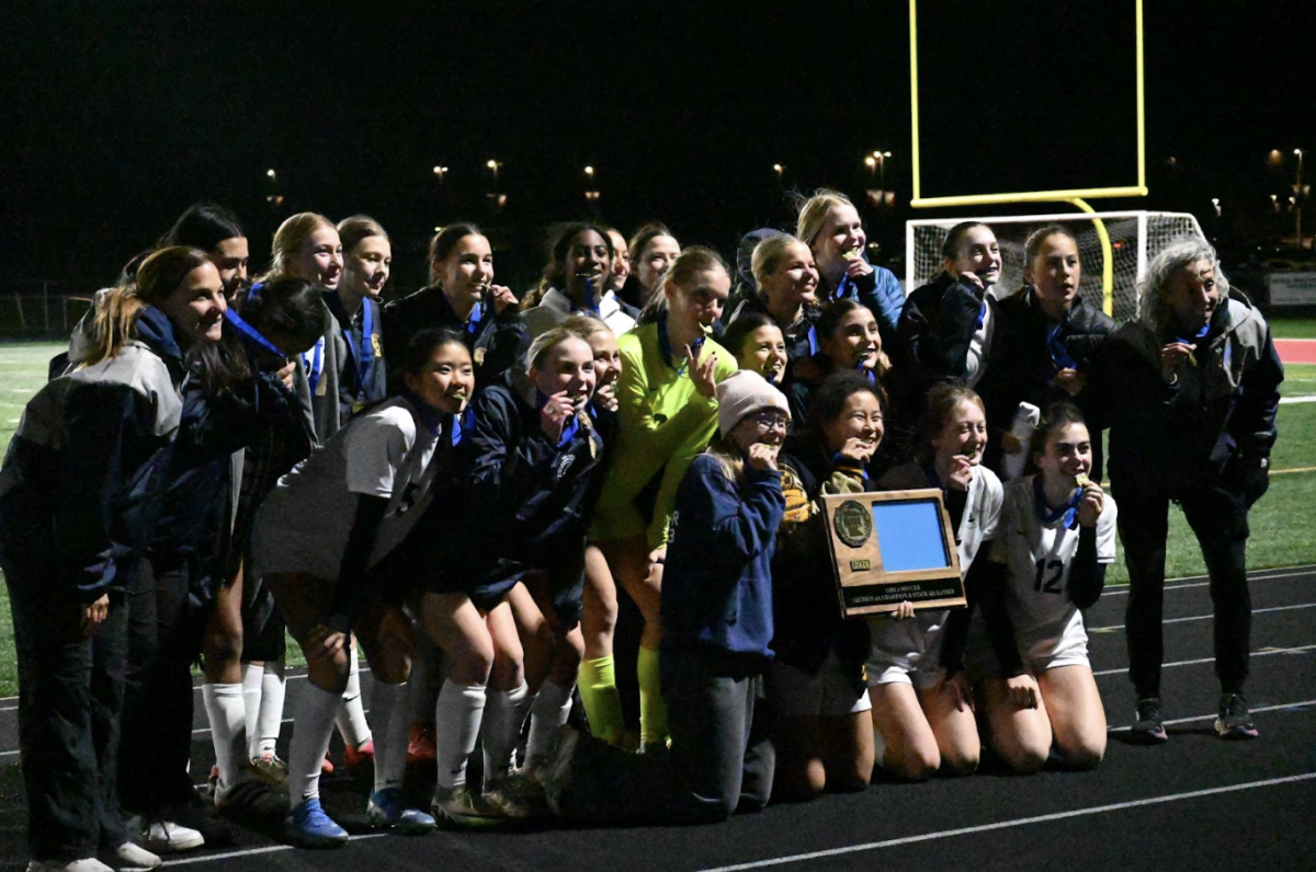 SAY “STATE.” GVS poses for a picture with their trophy in front of the bleachers. With this win, the Spartans are guaranteed a spot in the first round of the state tournament, where they will have the chance to repeat last year’s championship success.