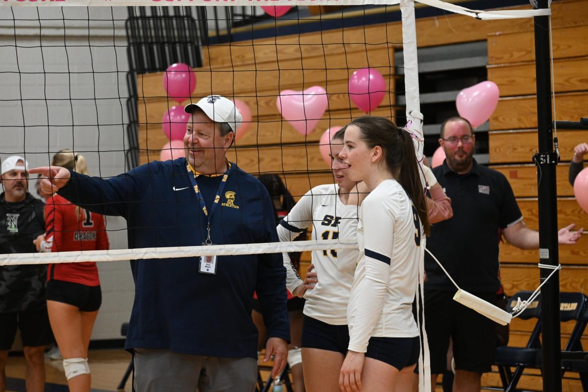 GETTING POINTERS. Captains Madelyn Moser and Lucy Thomas chat with Director of Athletics Paul Moyer as they take down the net.