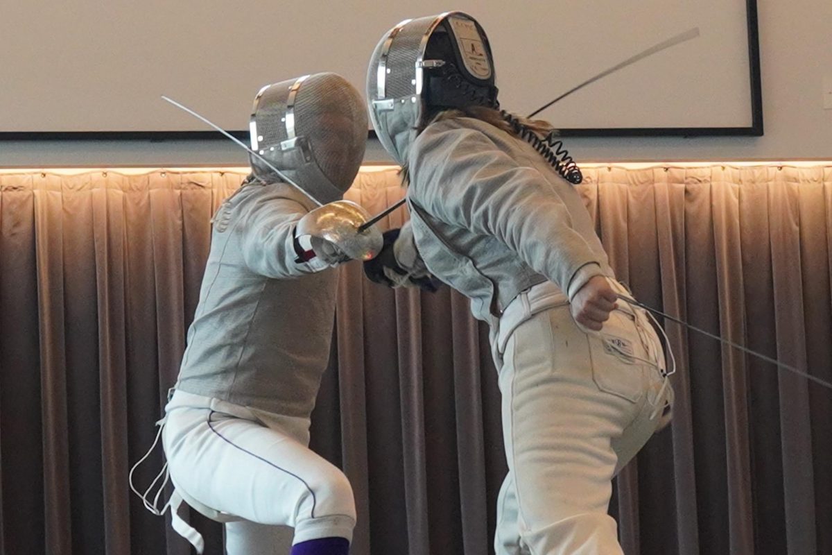 EN-GARDE. Junior Rowan Moore competes in fencing match and strikes their opponent.