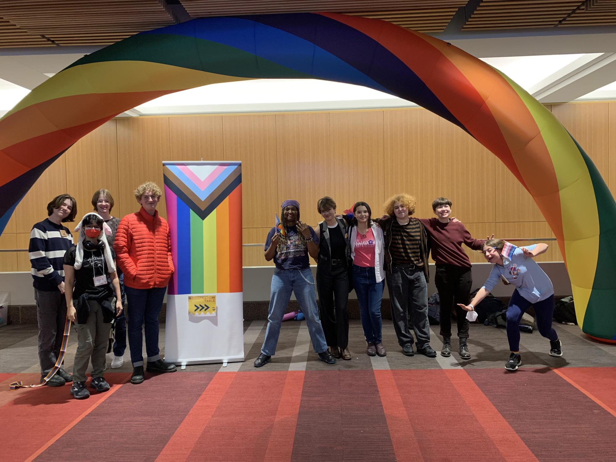 Q-QUEST. Students participating in Q-Quest pose for a group photo under a rainbow arch (Photo submitted by Jack Bettenburg).