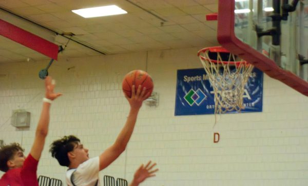 GOING UP. Senior Nathan Rock rises up for a layup being followed by a Scots defender. 