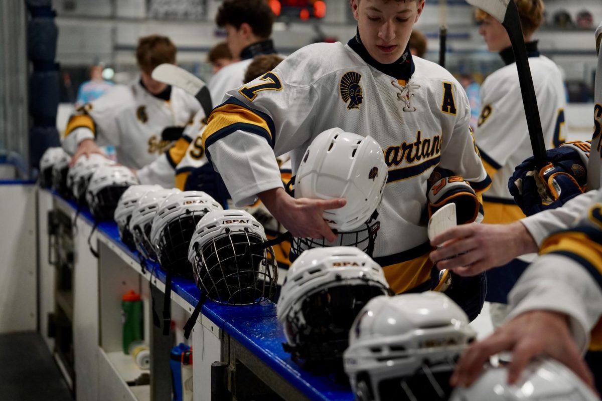 GEARING UP. Spartans gear up grabbing their helmets that they laid on the bench for the national anthem.  