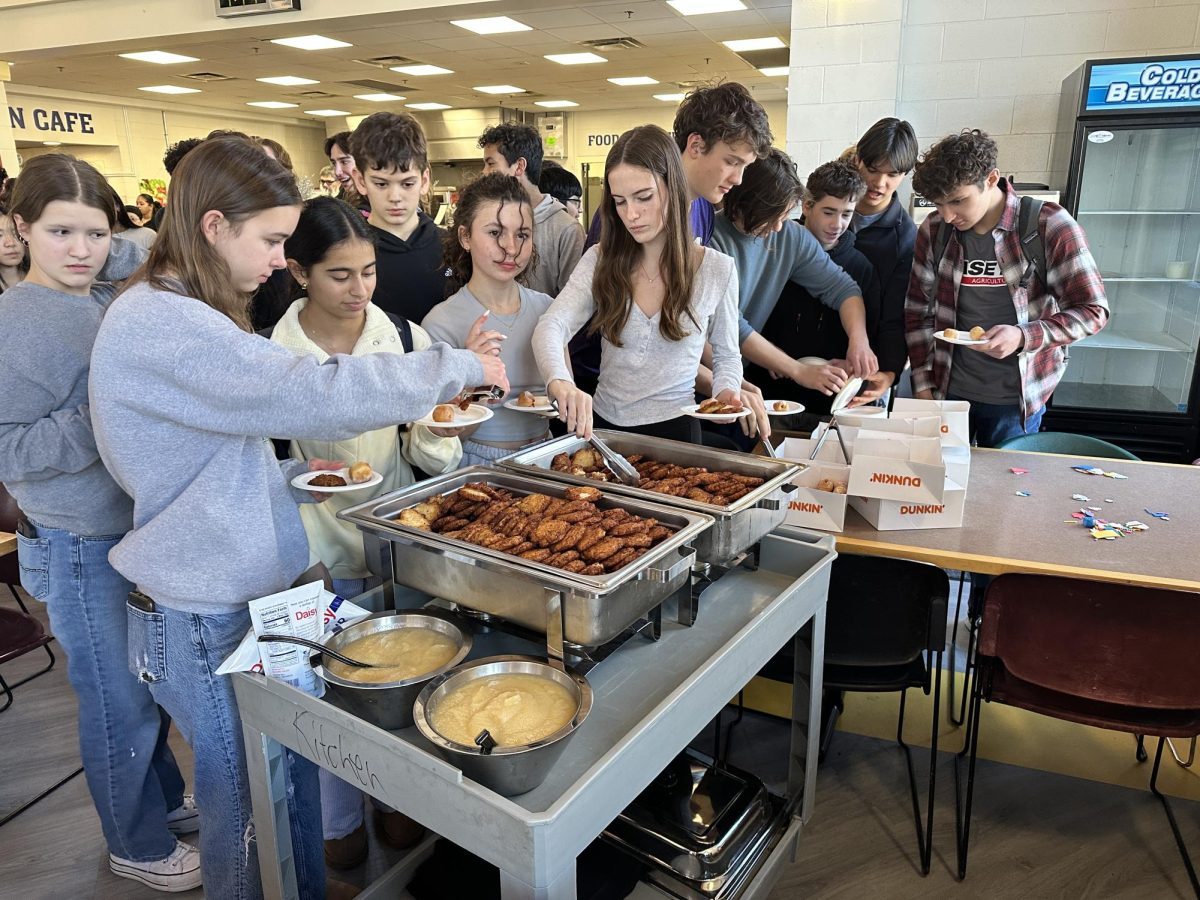 LOVING LATKES. Numerous students crowd around the food, gathering latkes and donuts. 