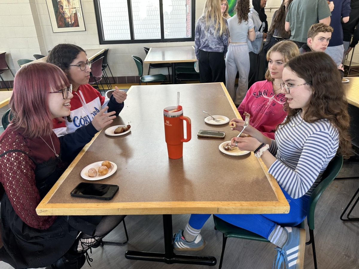 FOOD AND FRIENDS. Juniors Taryn Karasti, Frances Matthews, Frances Conrod-Wovcha, and Elzie Bieganek (left to right) talk and eat latkes and donut holes together. 