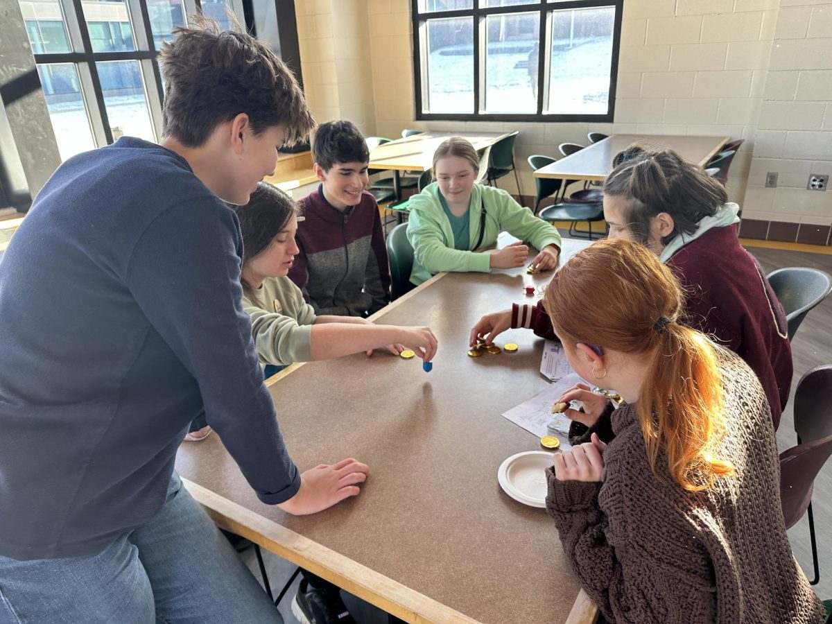 FIRST-YEAR FUN. First-years gather around a dreidel and compete for chocolate coins. 