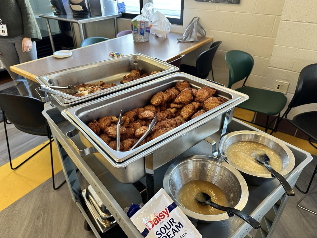 LEGENDARY LATKES. A cart holding two trays full of the traditional Jewish food, latkes, and toppings. Due to allergen concerns, Mishpacha leaders had to purchase pre-made latkes from Trader Joes before the celebration. "[Latkes] are better hommemade, which unfortunately, we couldn't do due to allergies. But the Trader Joes ones are a really good substitute" Mishpacha leader, Avi Coleman said. 