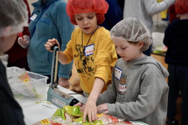 PRECISION. Students count how many bags of food they have packaged for each box to contain 320 meals per box.