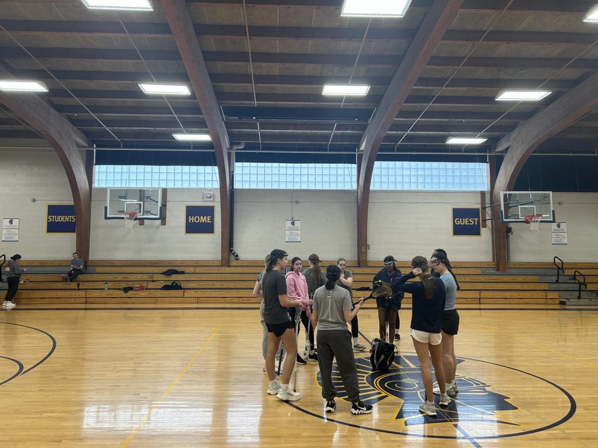 TOGETHER. The girls lacrosse team meets in the middle of practice to discuss drills.